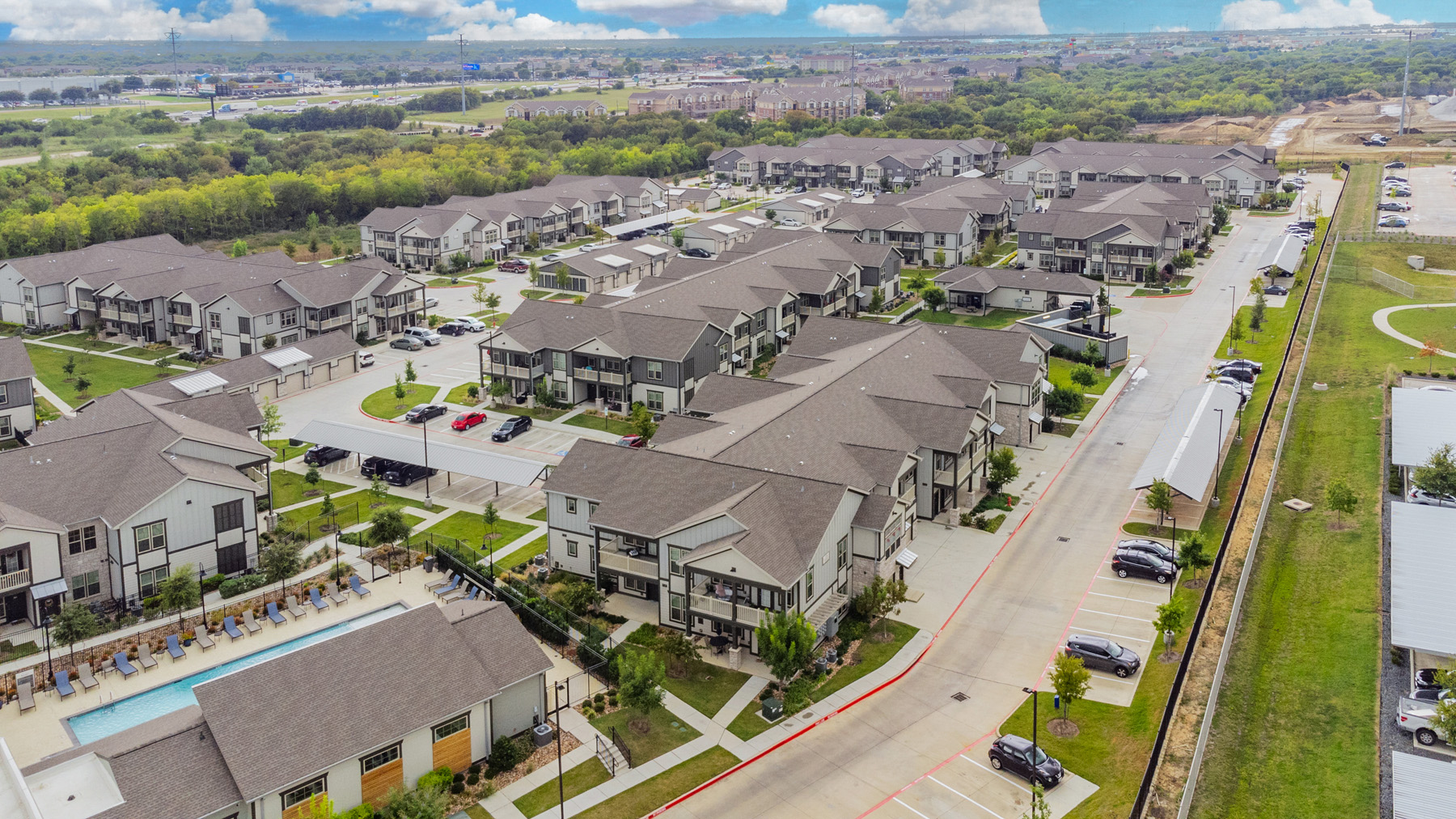 Aerial view of the property buildings at The Bradbury and the surrounding neighborhood area with surroundign greenery