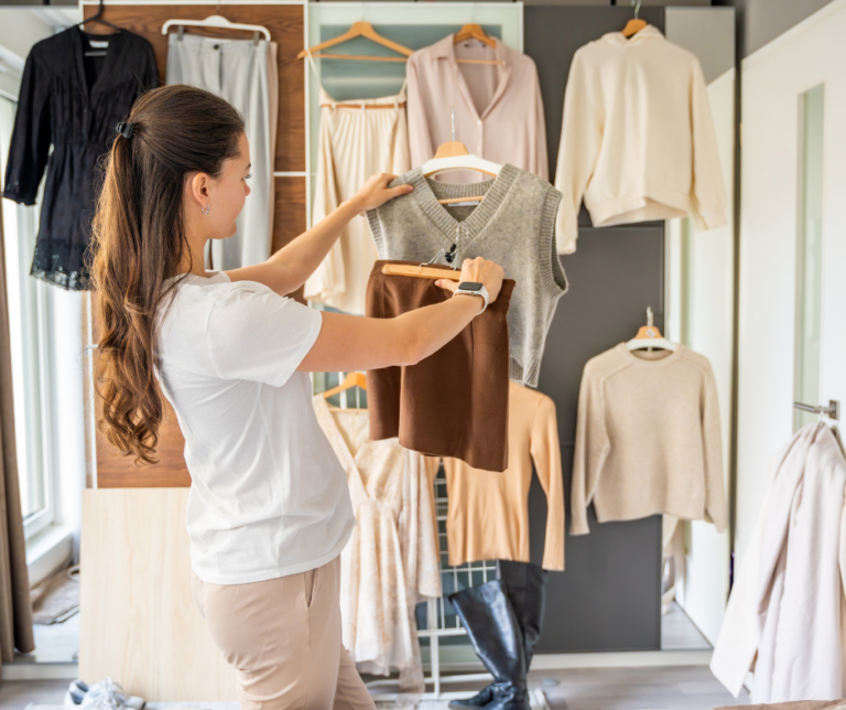 A woman sorting through clothing on hangers in front of her